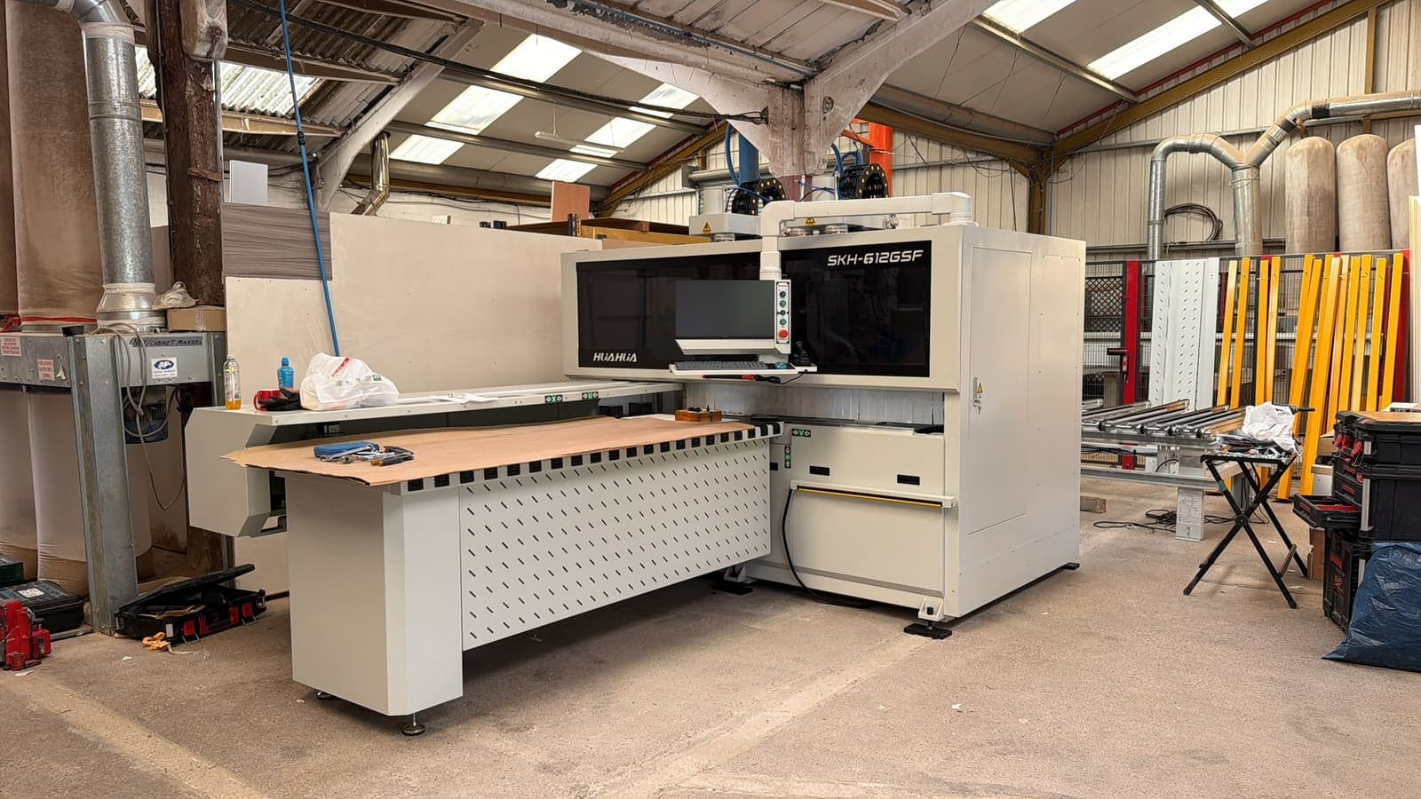 A newly installed Hua Hua CNC drilling machine standing in a workshop, tools still out on the bed